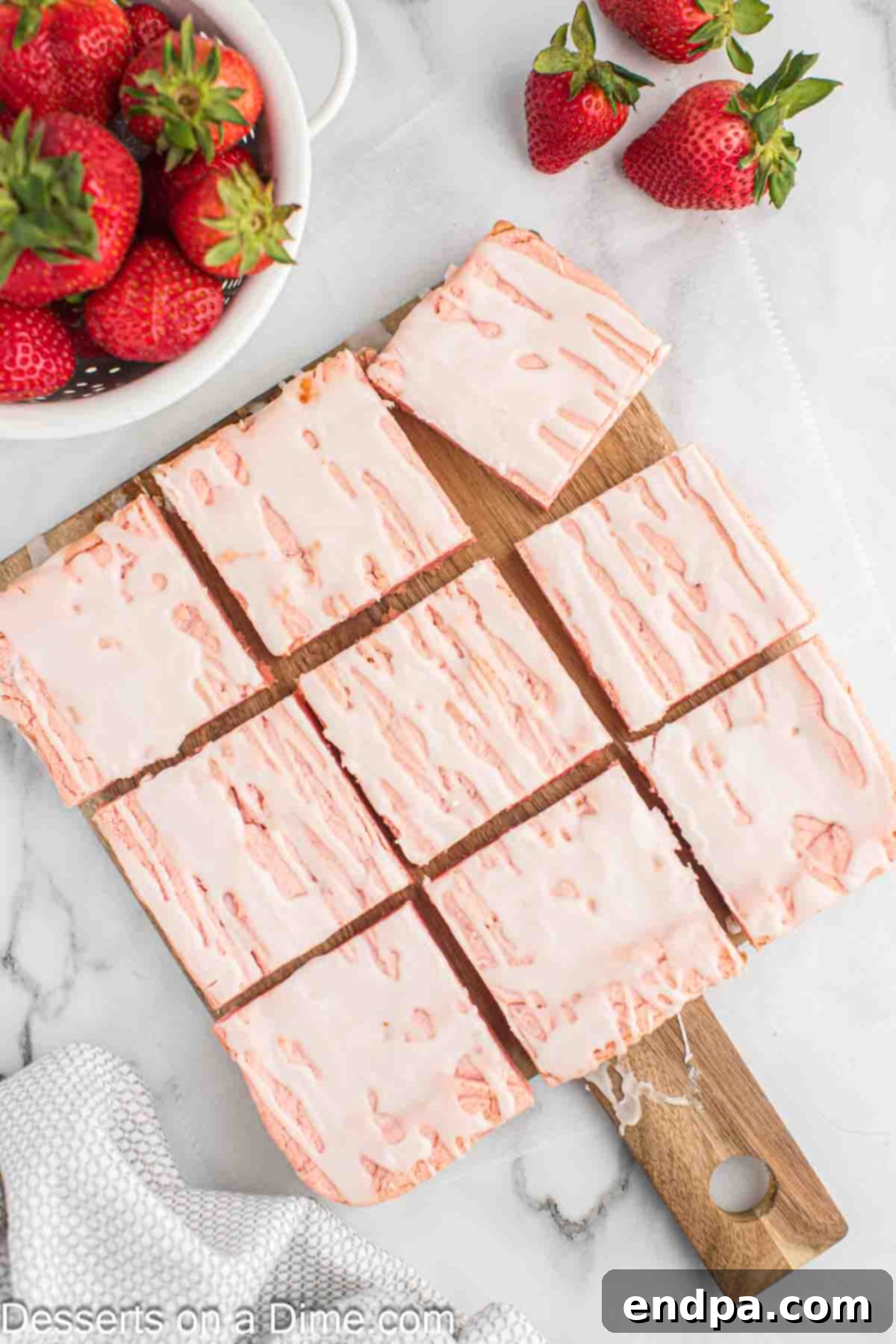 A serving of glossy strawberry brownies, perfectly cut into squares, on a decorative plate.