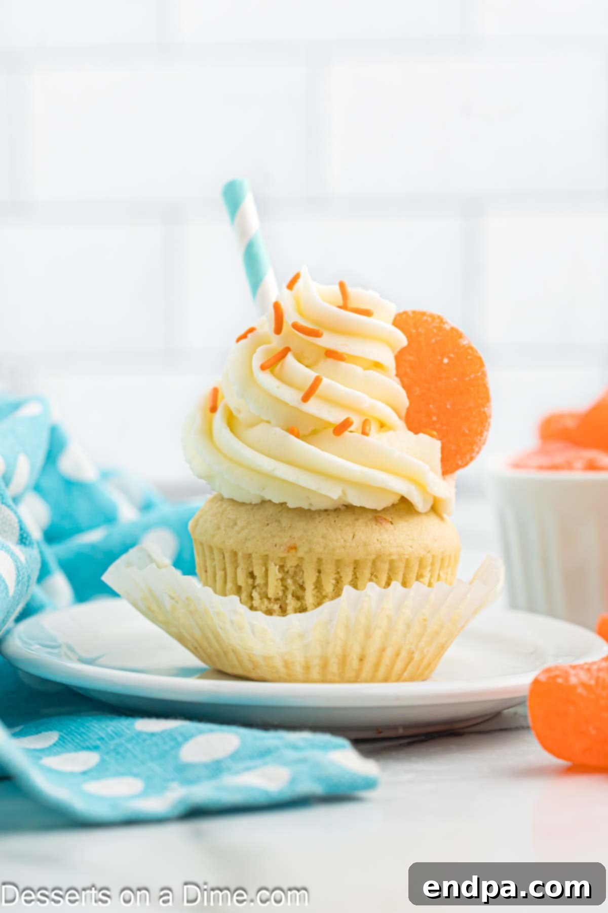 A perfectly frosted orange creamsicle cupcake on a white plate, showcasing its vibrant color and creamy texture, ready to be enjoyed.