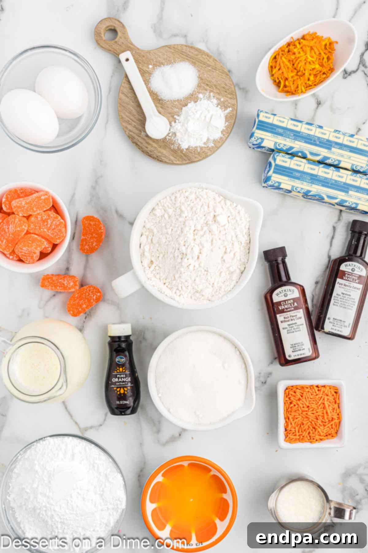 A selection of essential baking ingredients for orange creamsicle cupcakes, including flour, sugar, eggs, buttermilk, orange zest, and extracts, neatly arranged on a rustic wooden surface.
