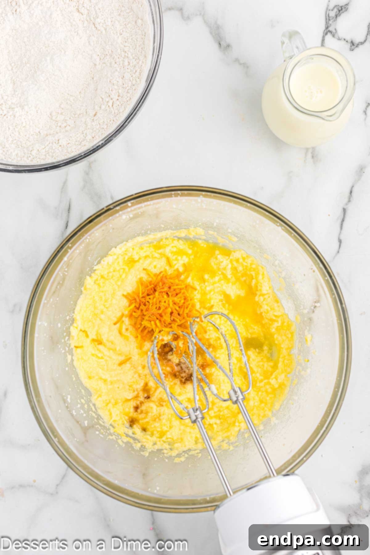 Eggs being added one by one to the creamed butter and sugar mixture in a mixing bowl, ensuring proper emulsification for the cupcake batter.