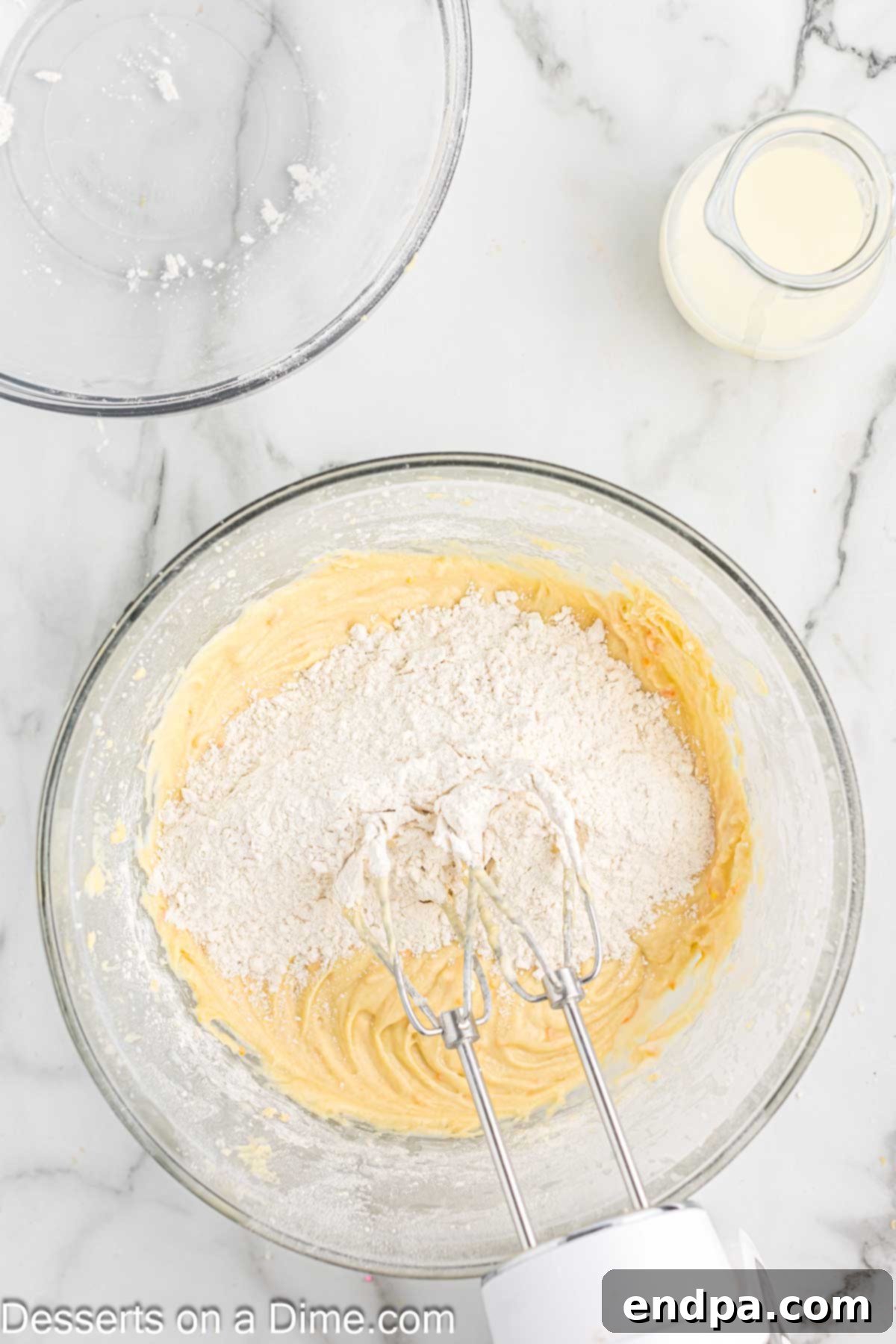 Alternating additions of dry ingredients and buttermilk to the wet mixture in a bowl, crucial for achieving the perfect cupcake batter consistency.