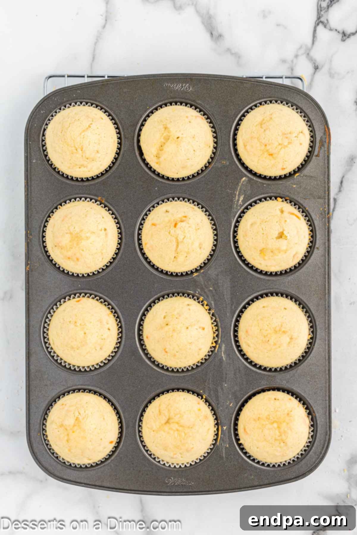 Freshly baked orange creamsicle cupcakes cooling on a wire rack, ready for frosting.