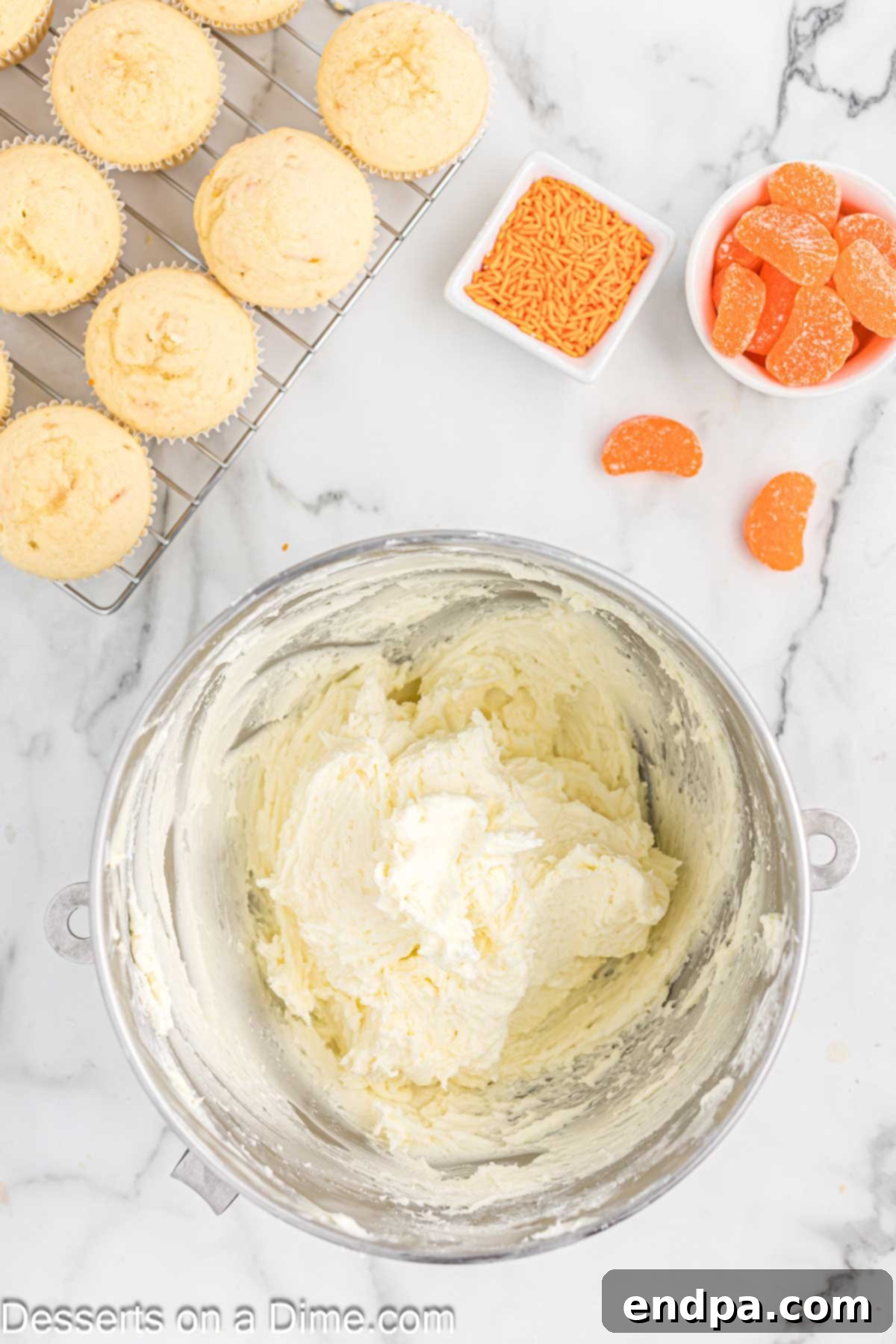 Powdered sugar being gradually added to the beaten butter, alternating with heavy cream and vanilla, to create the smooth creamsicle frosting.