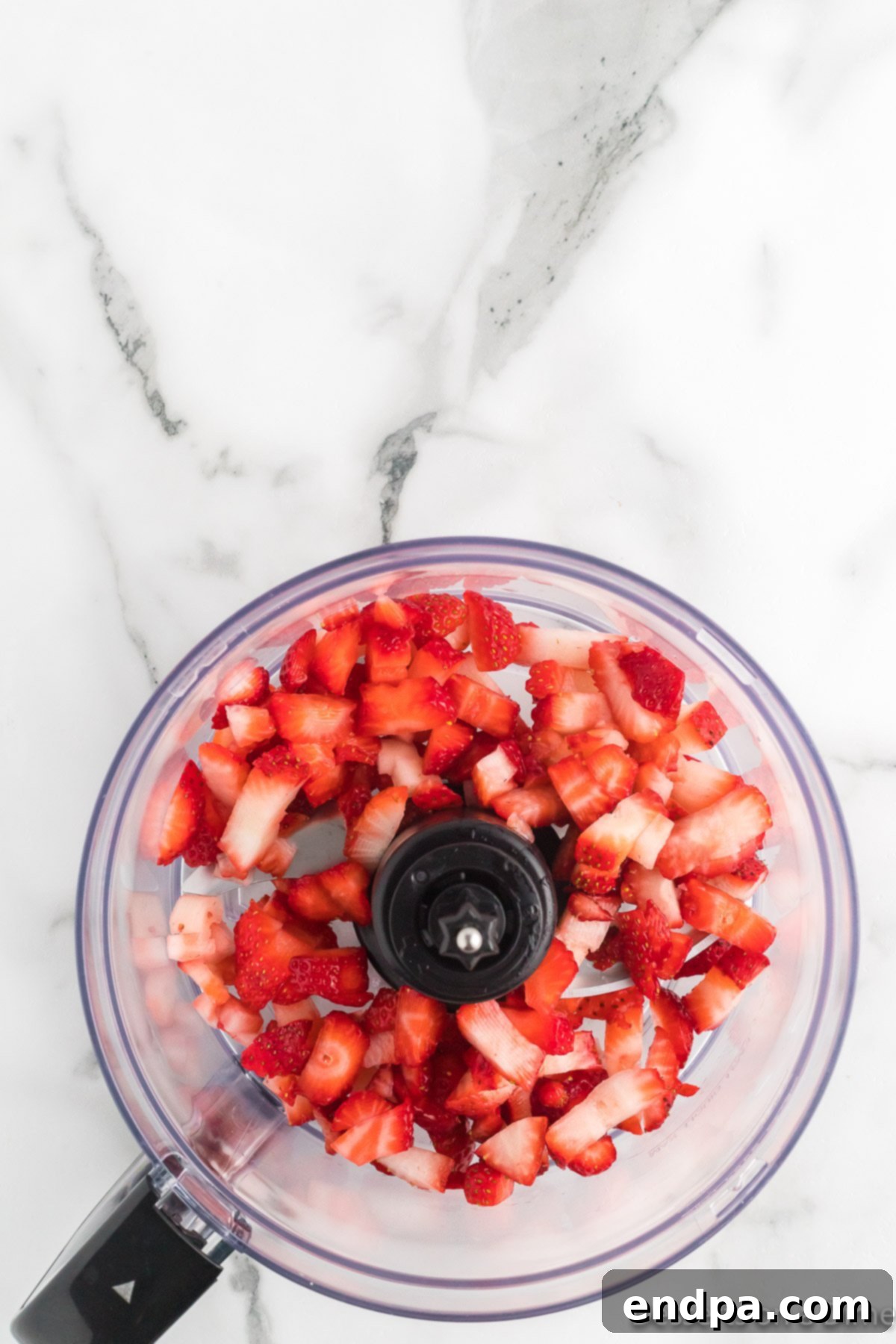 Diced fresh strawberries in a food processor, ready to be pureed.