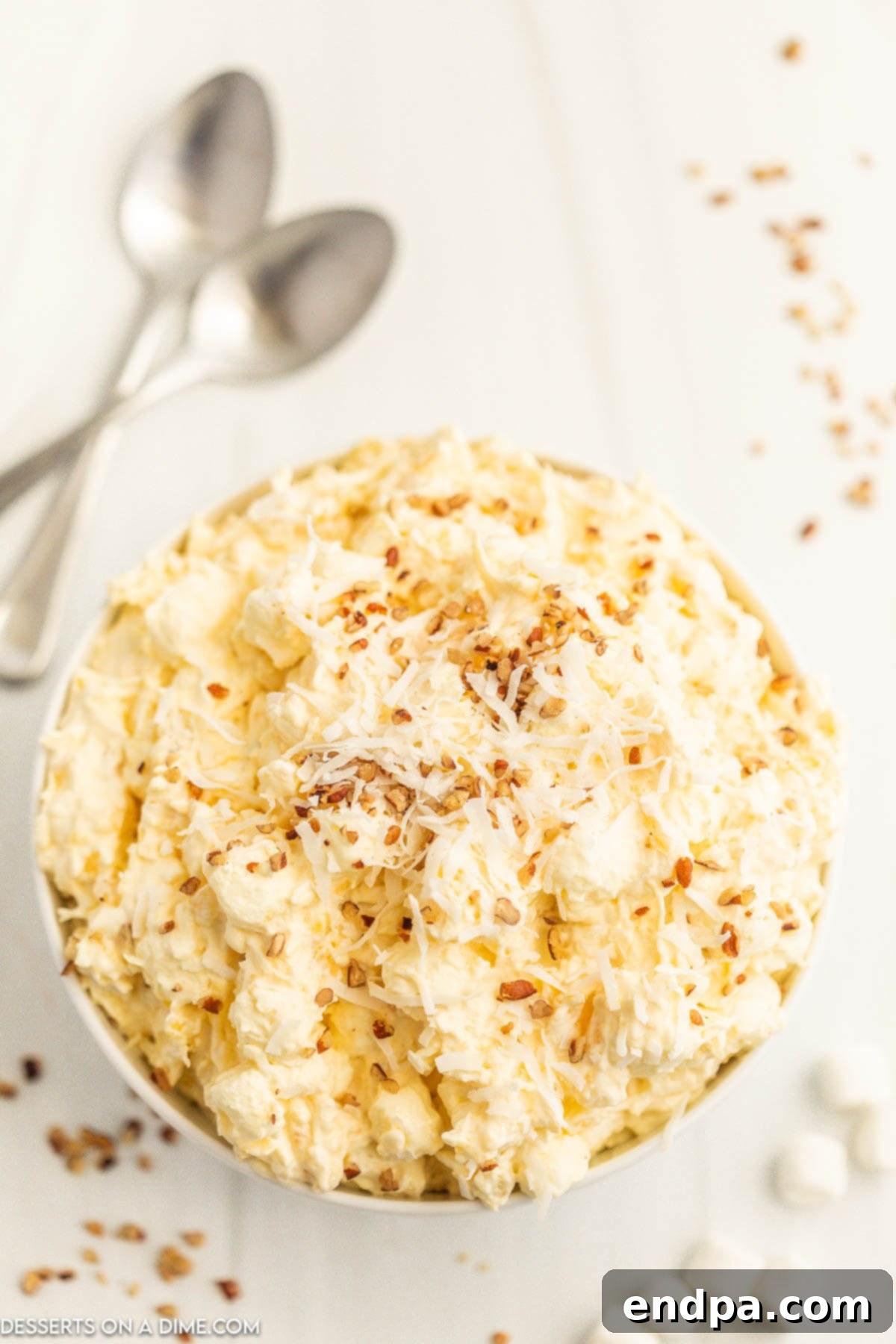 Tropical Pineapple Dream 2 A beautiful bowl of Pineapple Fluff, garnished with toasted coconut flakes and chopped pecans, ready to be served.