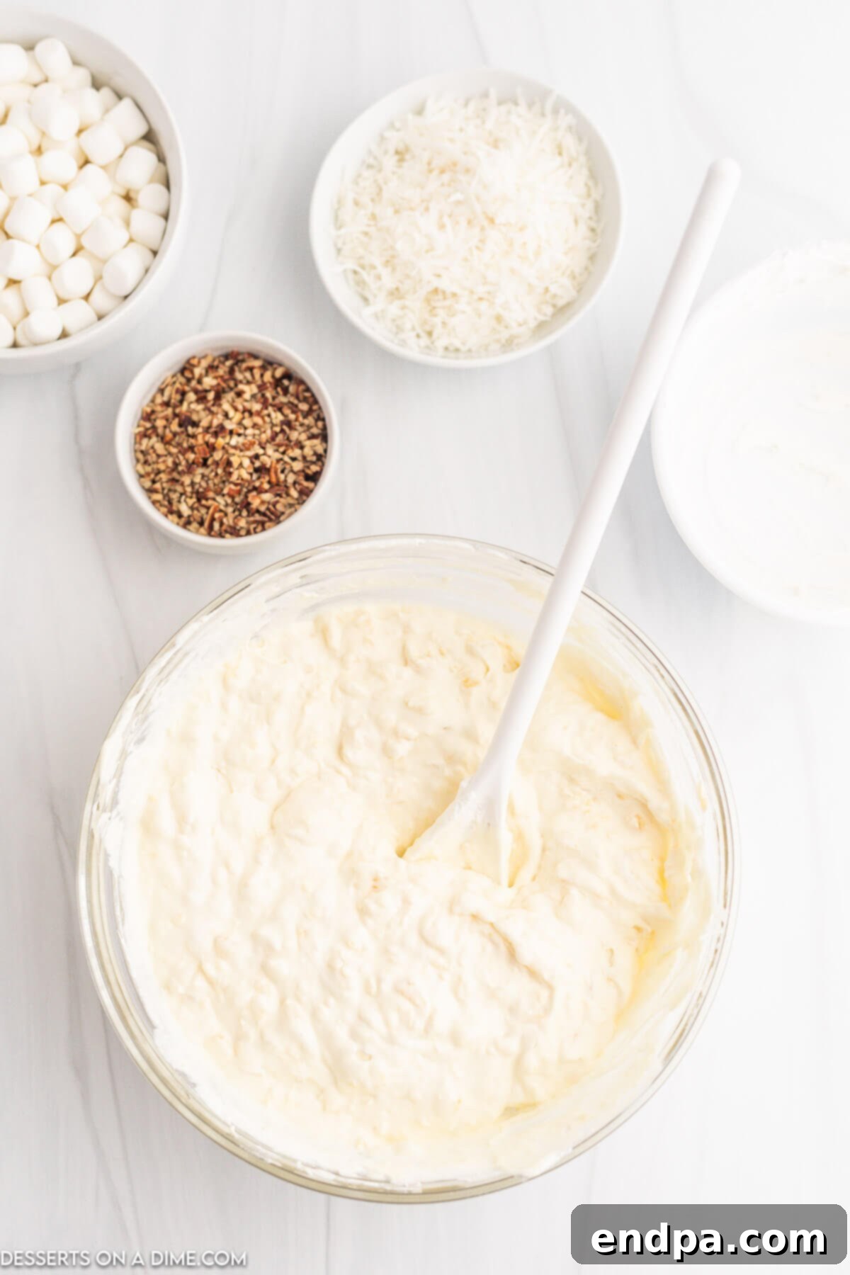 Tropical Pineapple Dream 5 Whipped topping being carefully folded into the pineapple and pudding mixture in a mixing bowl.