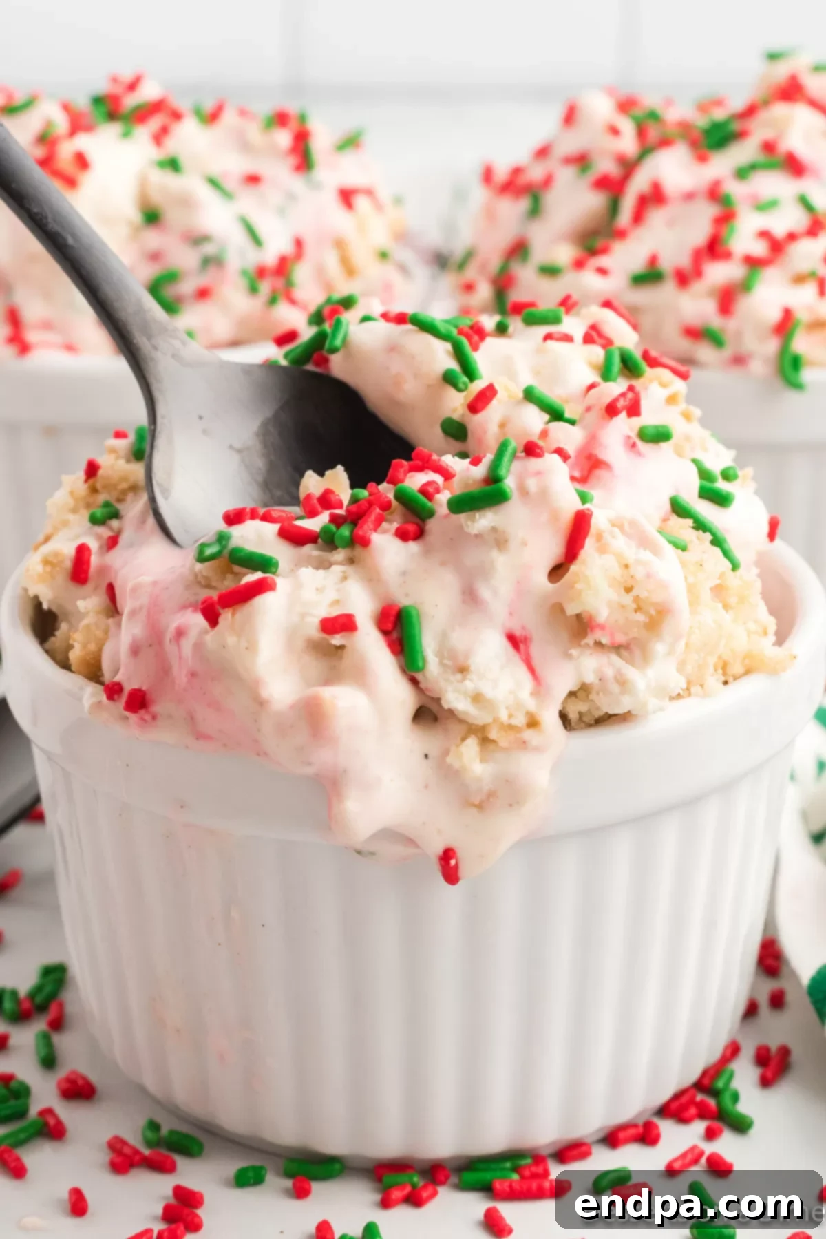 Merry Melts 14 A close-up shot of a scoop of homemade Christmas Ice Cream in a bowl, showcasing the cookie crumbles, white chocolate chunks, and festive sprinkles.