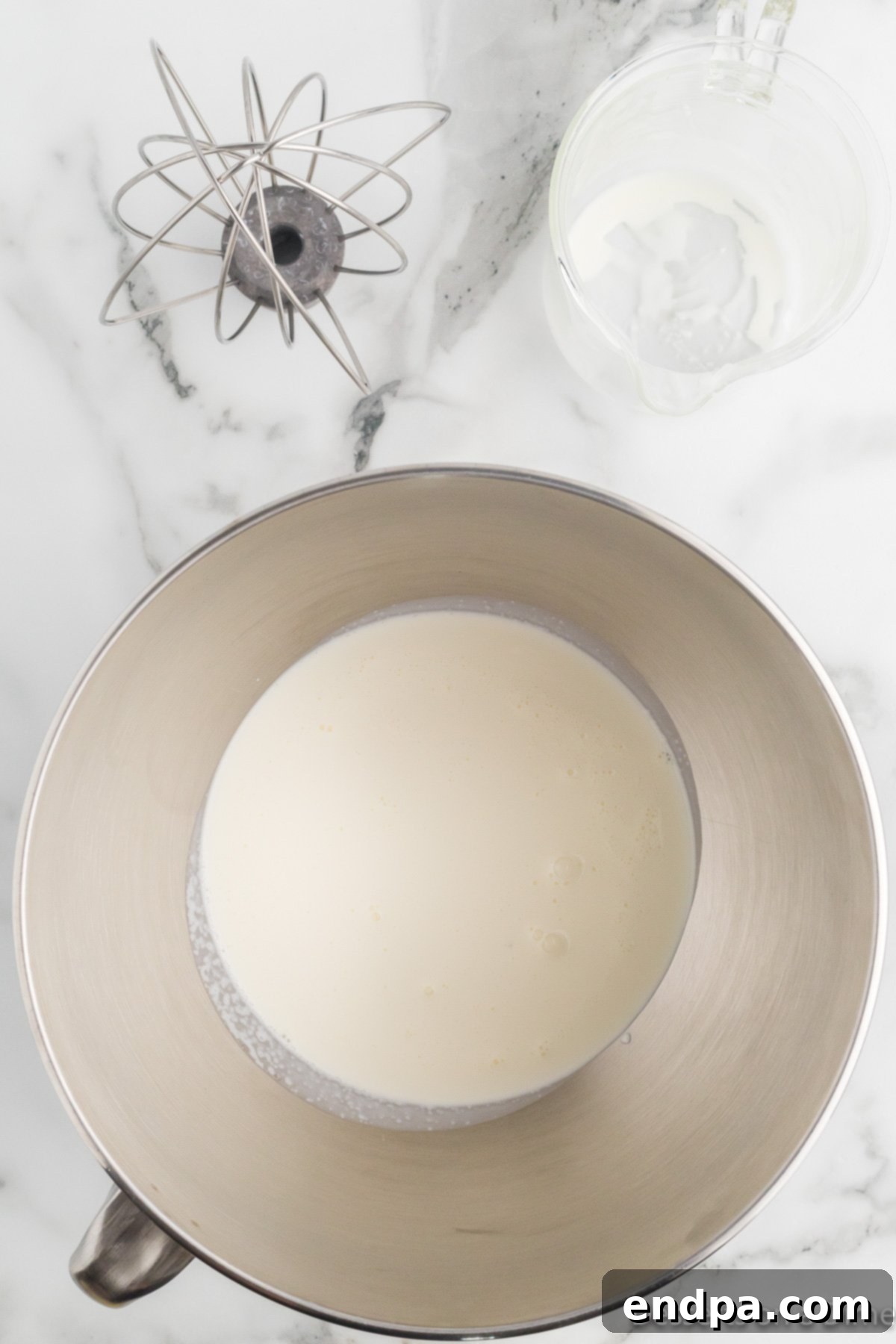 Merry Melts 4 Heavy cream being whipped in a large mixing bowl with an electric mixer.