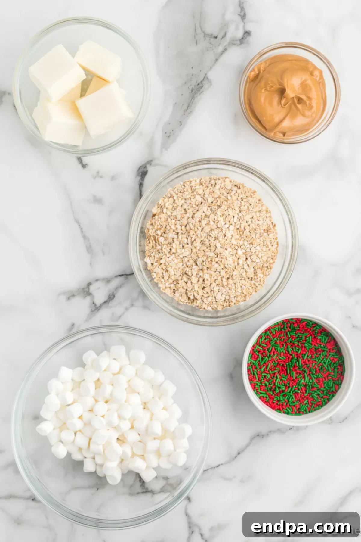 Festive No-Bake Delights 3 Key ingredients laid out for Christmas No Bake Cookies: white chocolate bark, peanut butter, quick oats, mini marshmallows, and festive sprinkles.