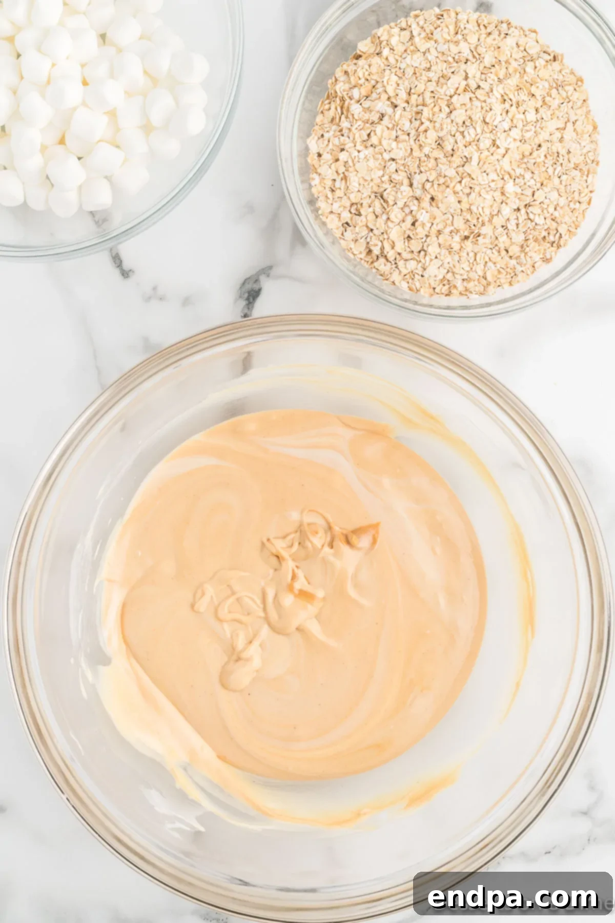 Festive No-Bake Delights 5 Creamy peanut butter being stirred into melted white chocolate bark until fully combined.