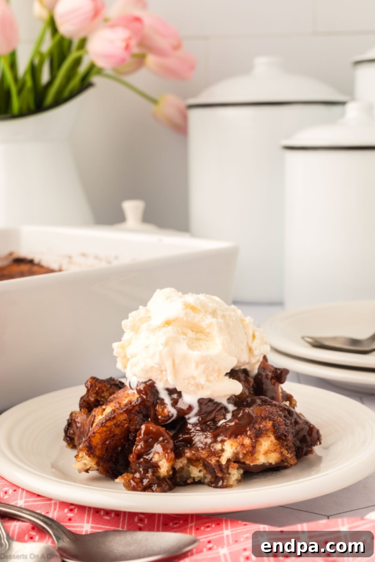A serving of chocolate cobbler on a plate topped with ice cream