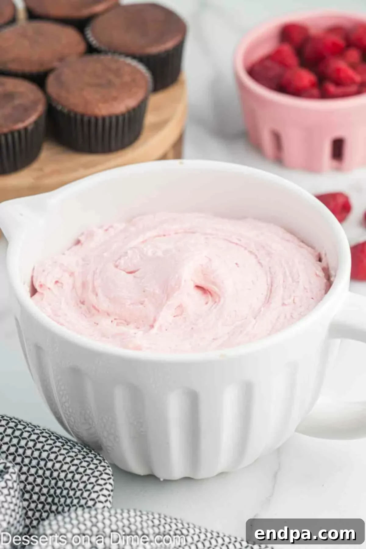 Freshly made raspberry frosting in a white ceramic bowl, ready to be used.