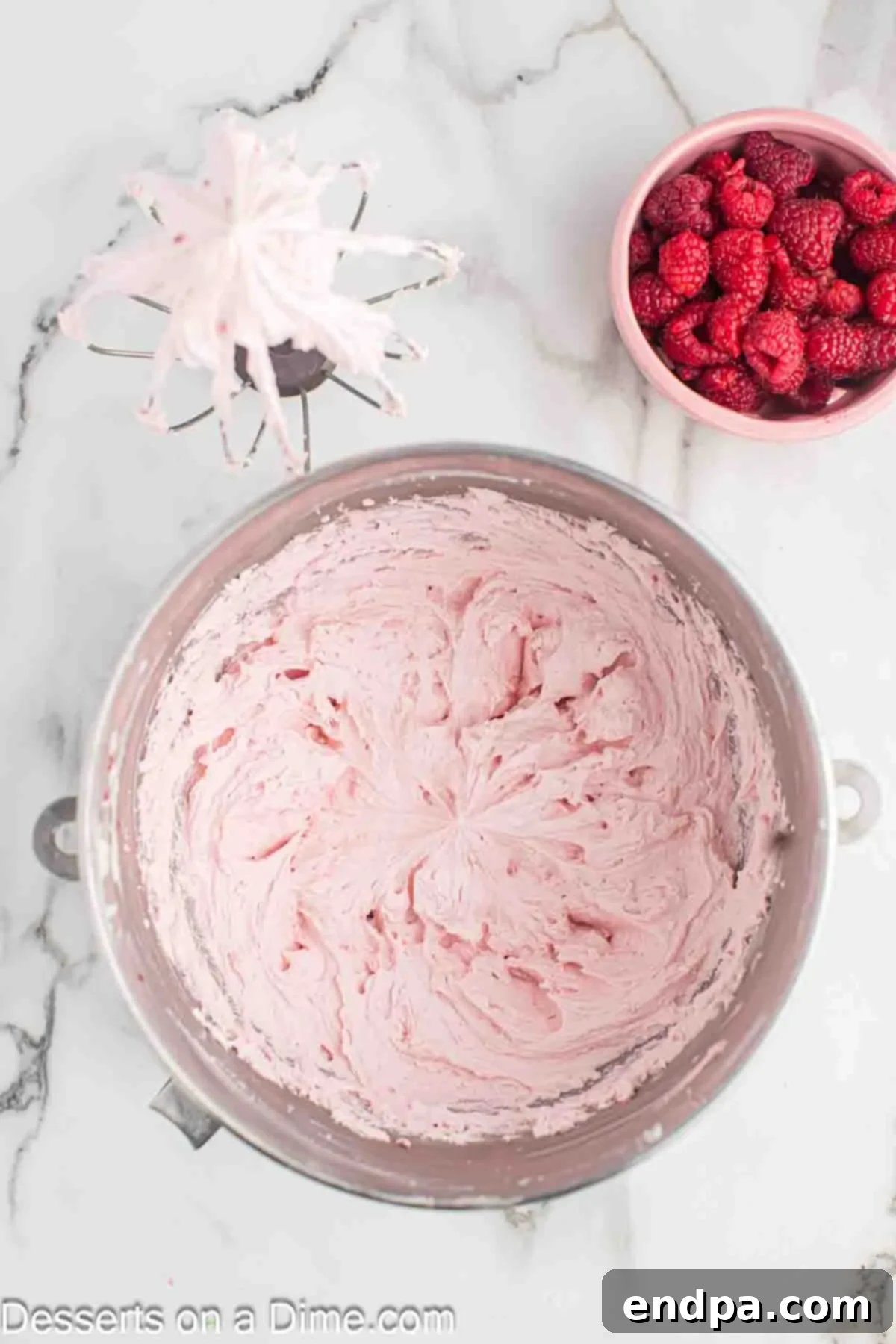 The raspberry puree being added to the creamed butter and sugar mixture in a mixing bowl.