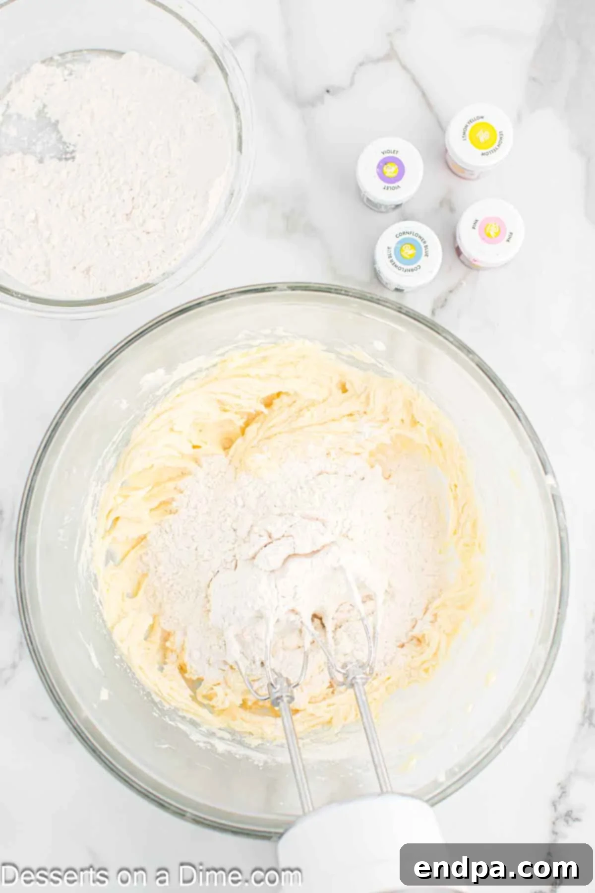 Rainbow Unicorn Drops 7 Flour gradually being added to the wet ingredients in a mixing bowl.