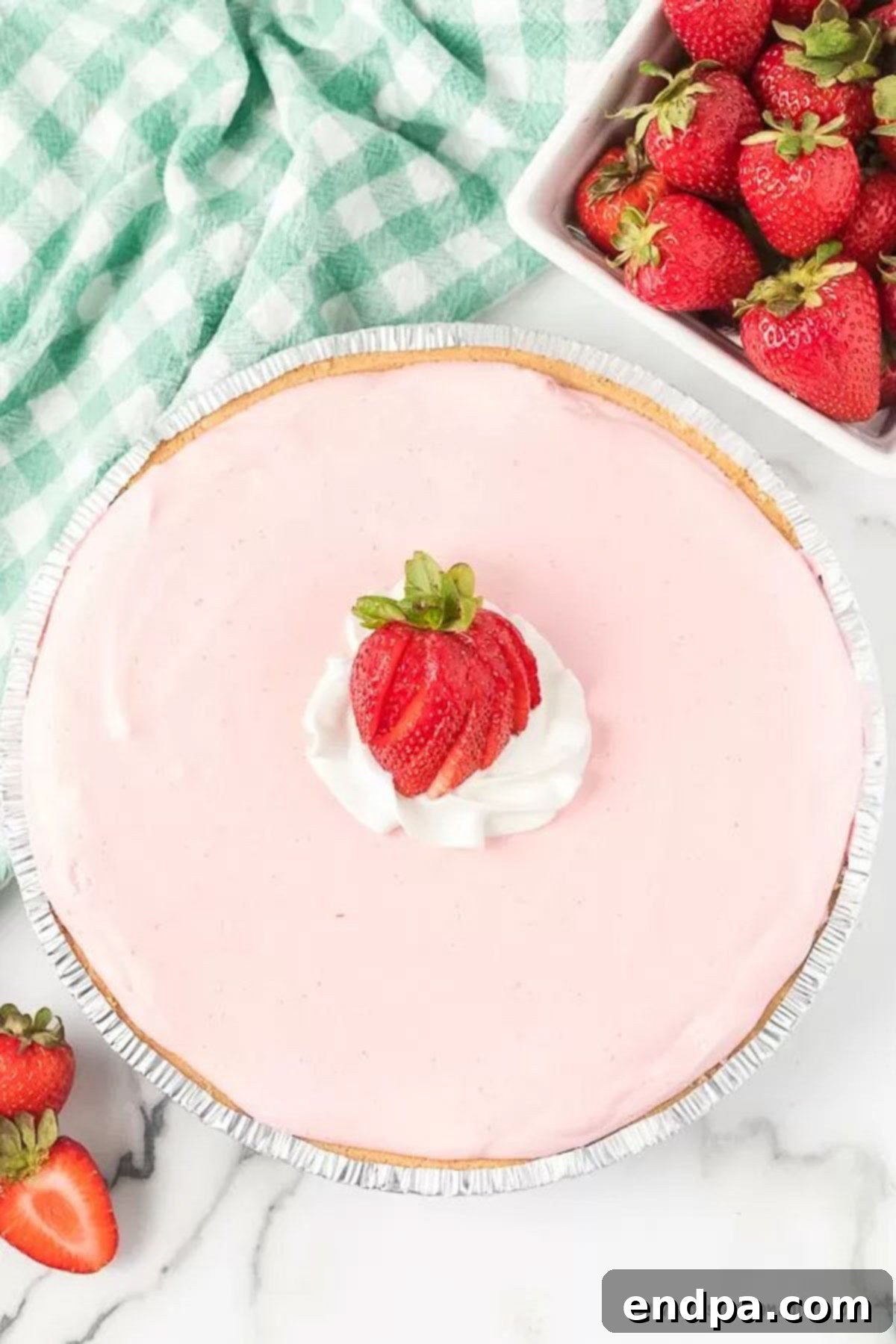 A whole strawberry jello pie with slice strawberries, ready to be served