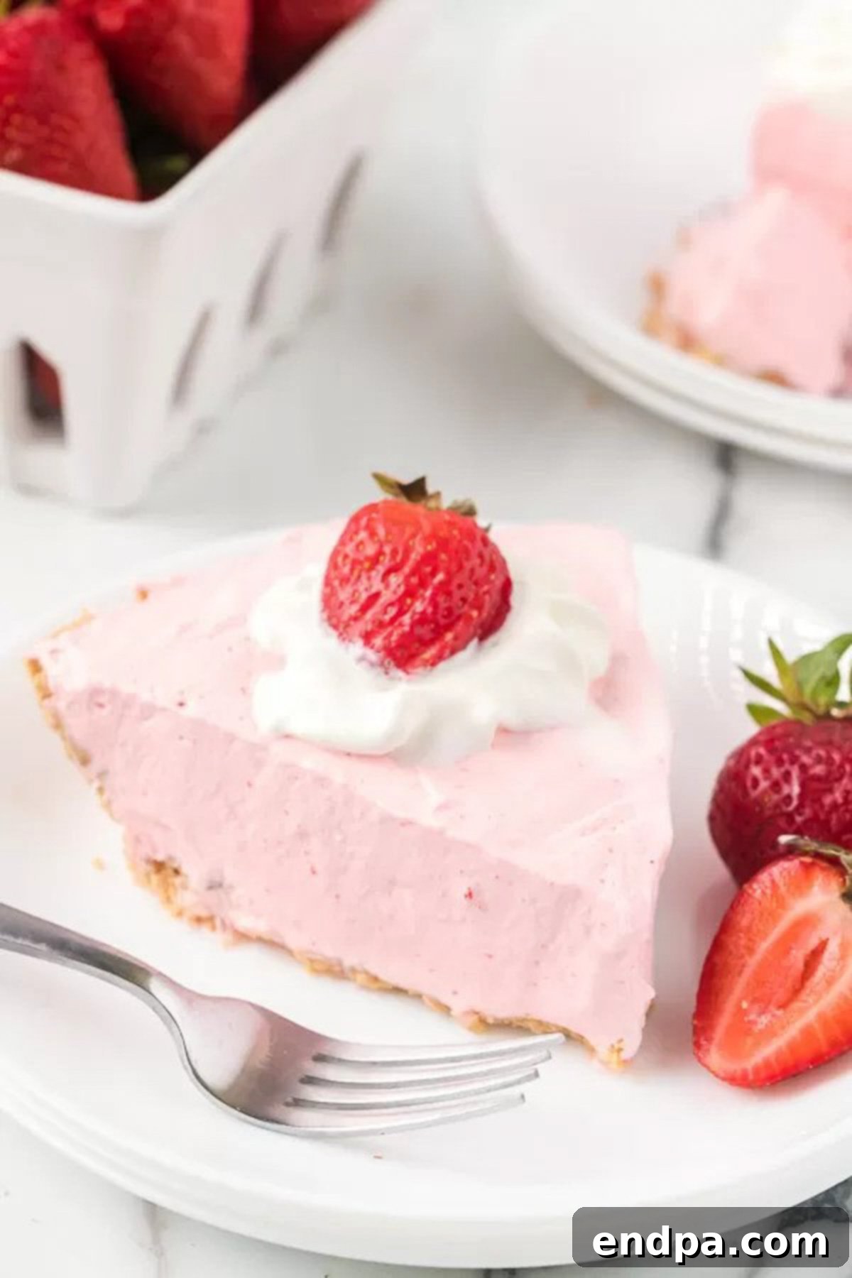 A slice of Strawberry Jello pie with fresh strawberries on a white plate