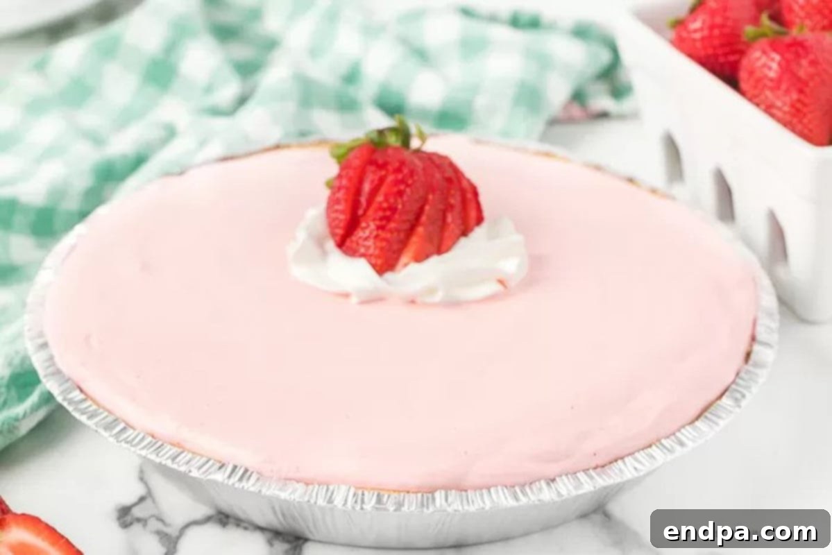 A whole Strawberry Jello Pie with fresh sliced strawberries on top, set in a graham cracker crust
