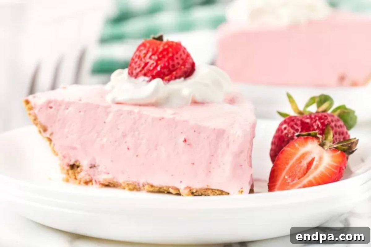A slice of Strawberry Jello pie on a white plate, garnished with whipped cream and fresh strawberries