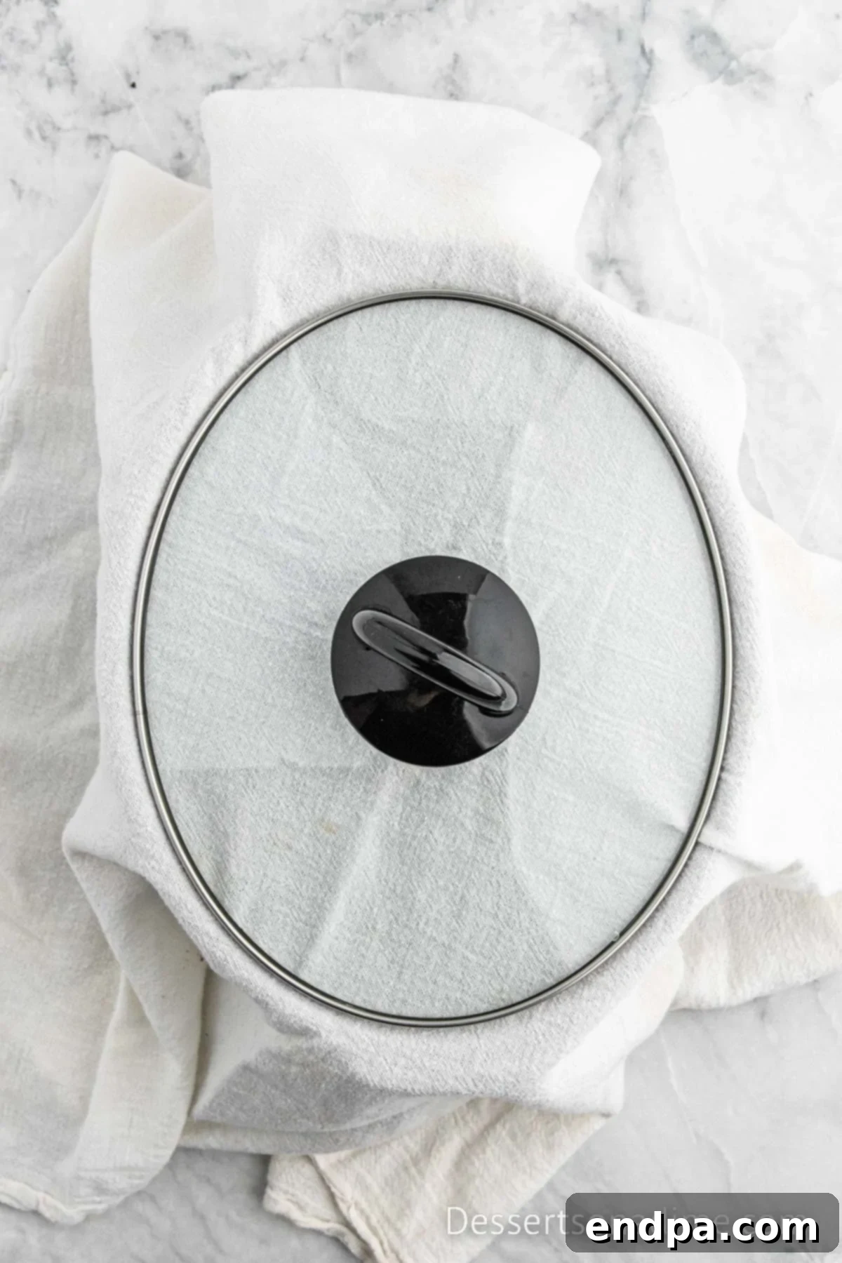 Crockpot lid covered with a dish towel to absorb moisture.