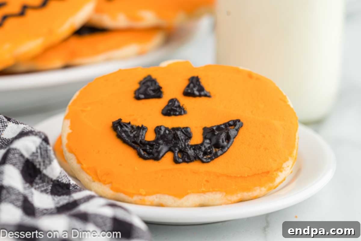 Frightfully Delicious Halloween Cookies 2 Festive Halloween sugar cookie on a plate, decorated like a jack-o'-lantern.