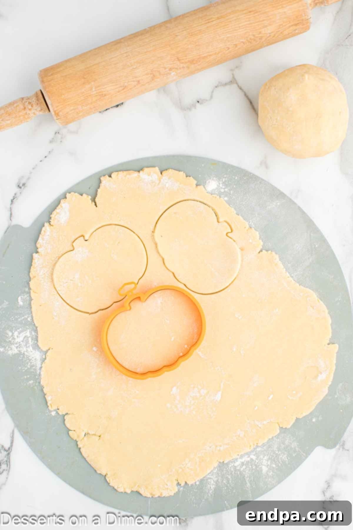 Frightfully Delicious Halloween Cookies 7 Sugar cookie dough rolled out and cut into pumpkin shapes with cookie cutters.