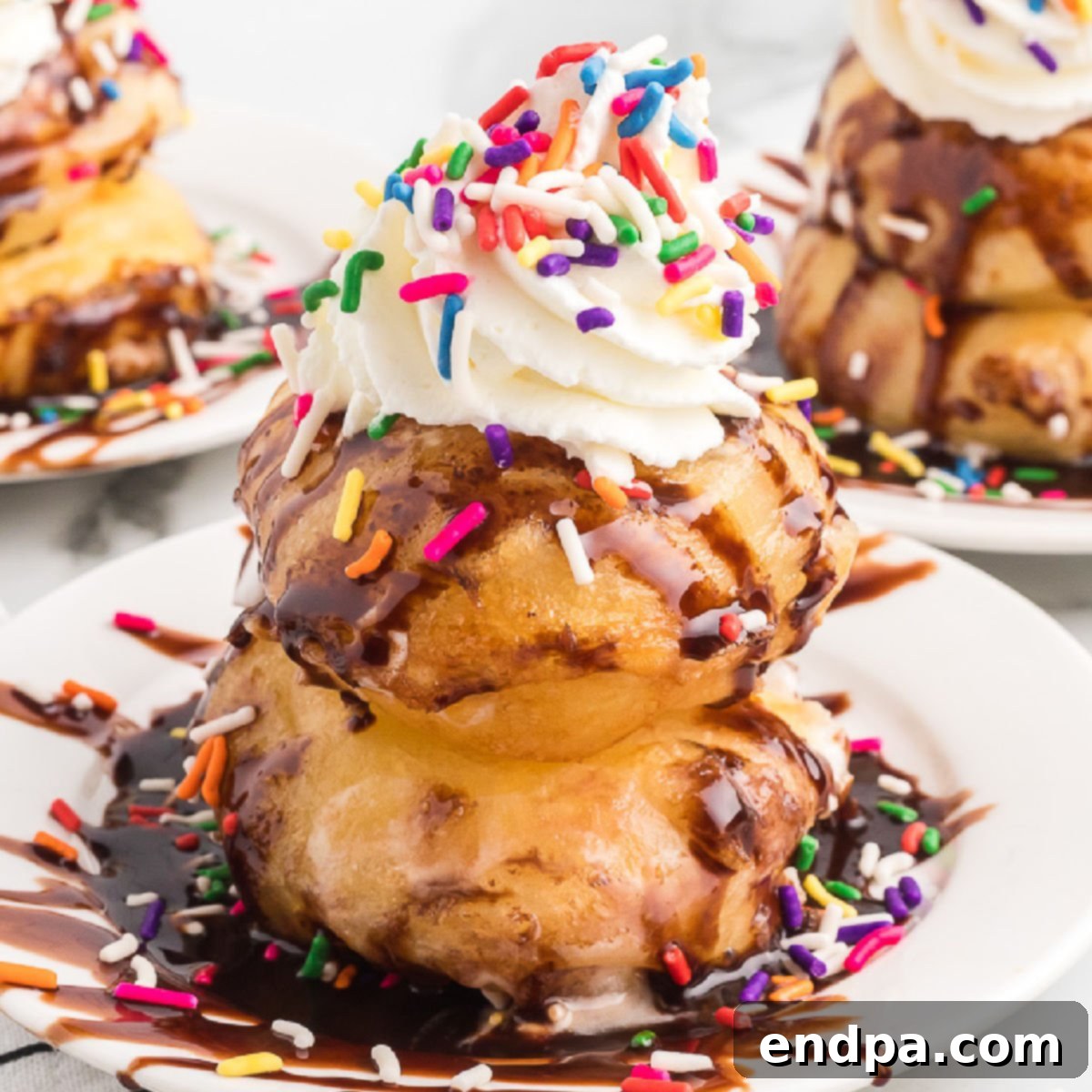 A stack of fried marshmallows with whipped cream and sprinkles.