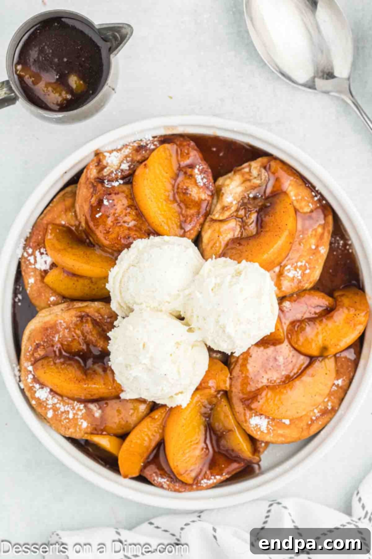 Deep fried peach cobbler topped generously with vanilla ice cream, showcasing the golden fried biscuits and juicy peach filling.