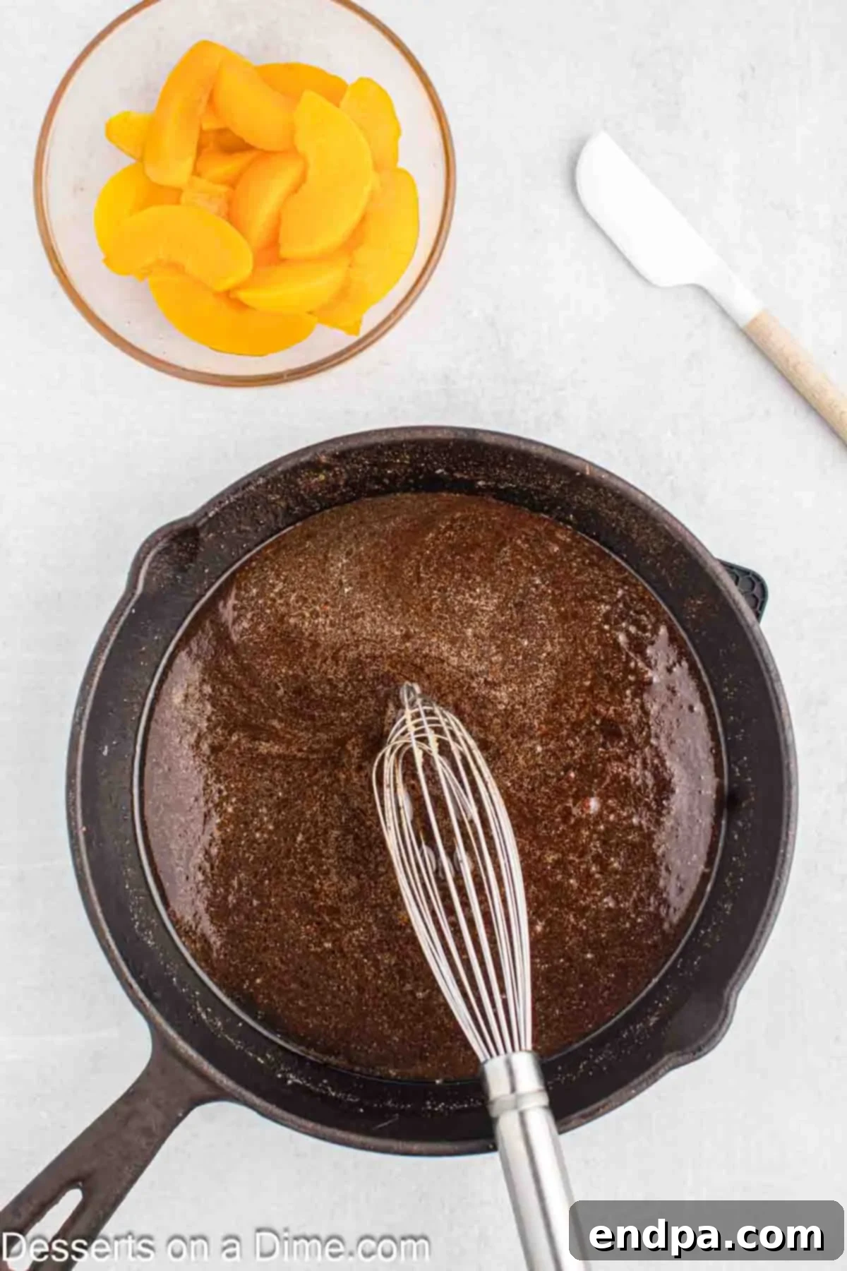 Butter, brown sugar, cinnamon, nutmeg, and allspice combined in a skillet, whisked together with peach juice.