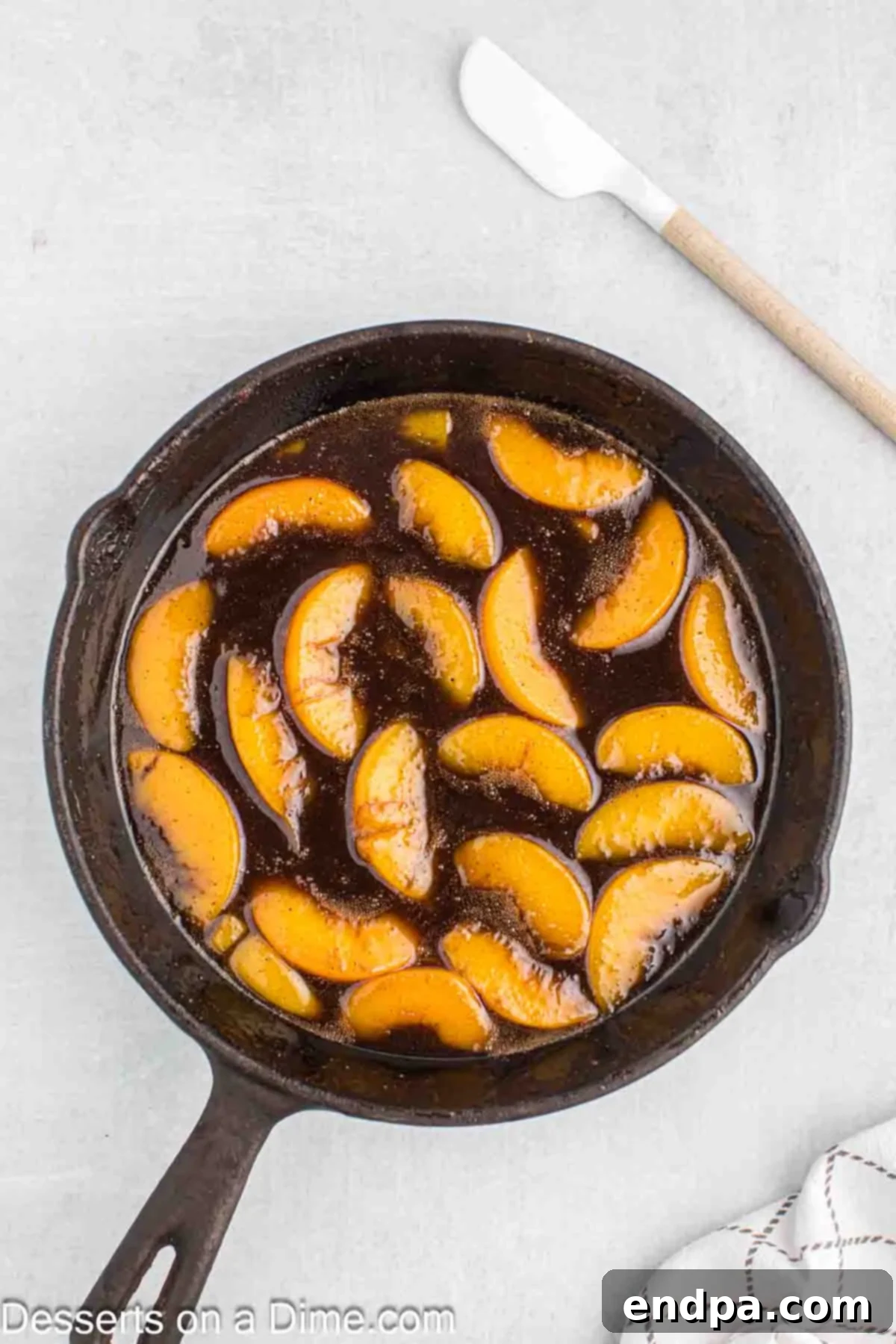 Sliced peaches being added to the simmering spice and brown sugar mixture in a skillet.
