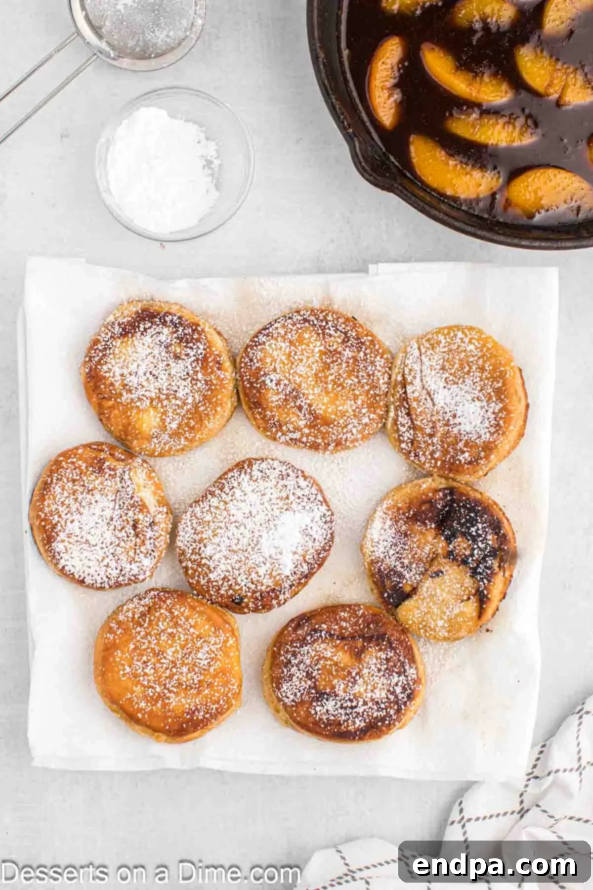 Freshly fried biscuits generously sprinkled with powdered sugar on a plate.