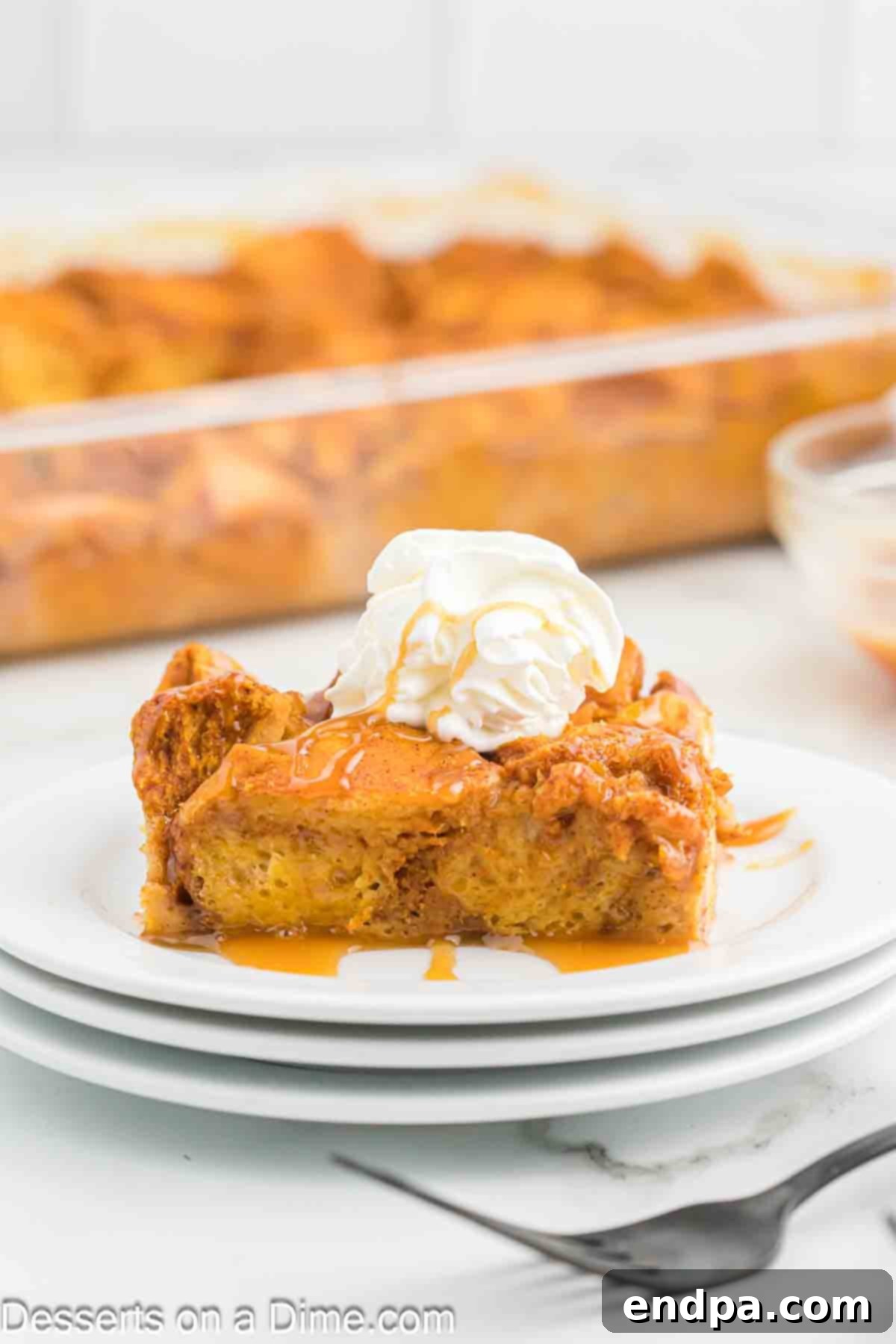 A serving of pumpkin bread pudding on a plate topping with whipped cream