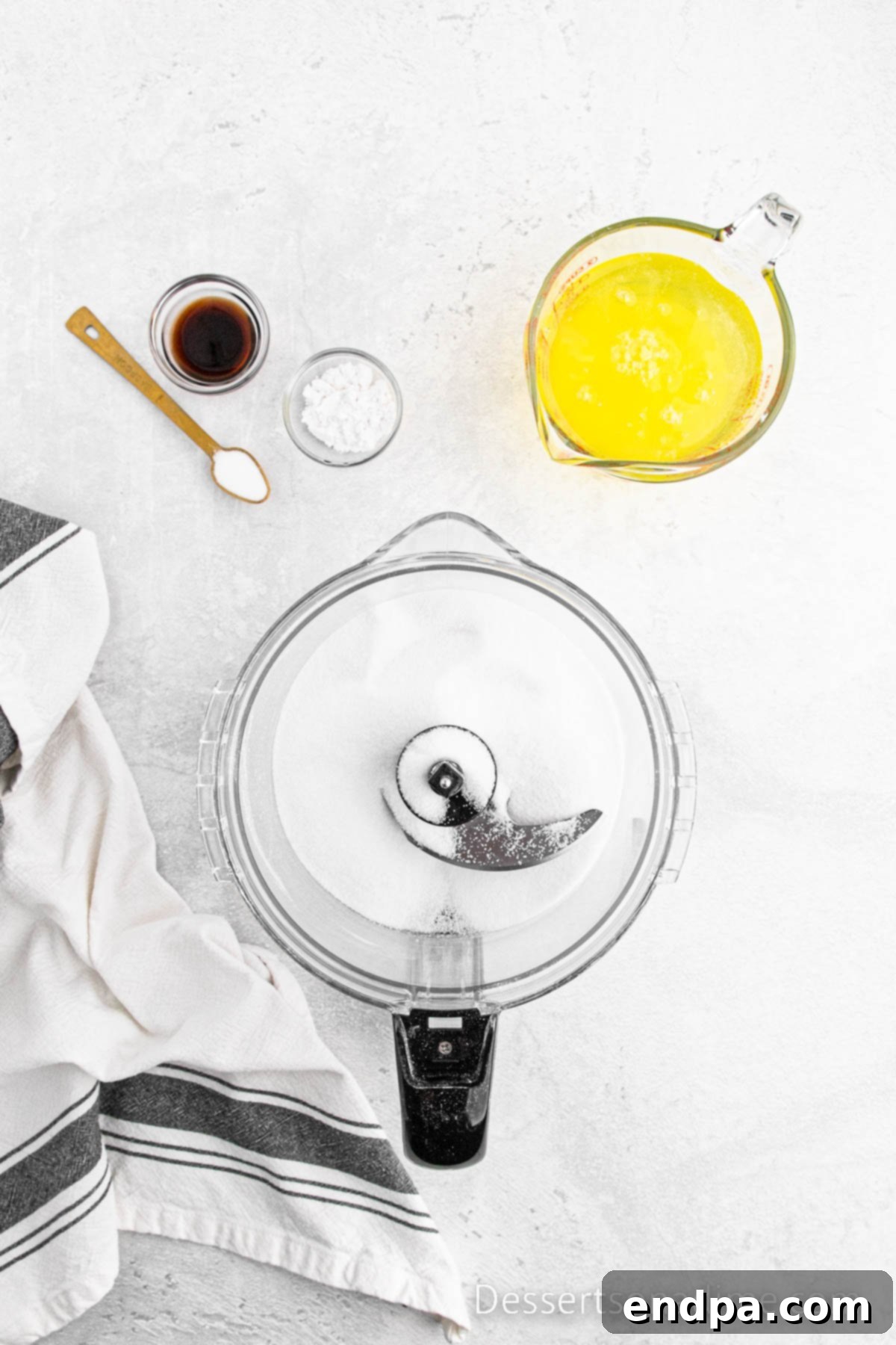 Food processor with granulated sugar being pulsed until fine and powdery.