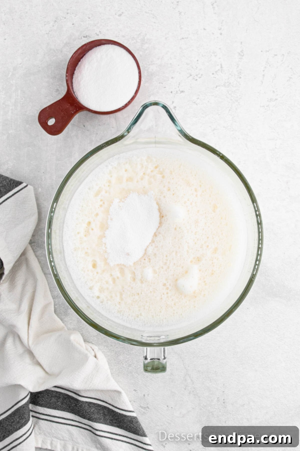 Stand mixer whipping egg whites and cream of tartar to a light and foamy consistency.