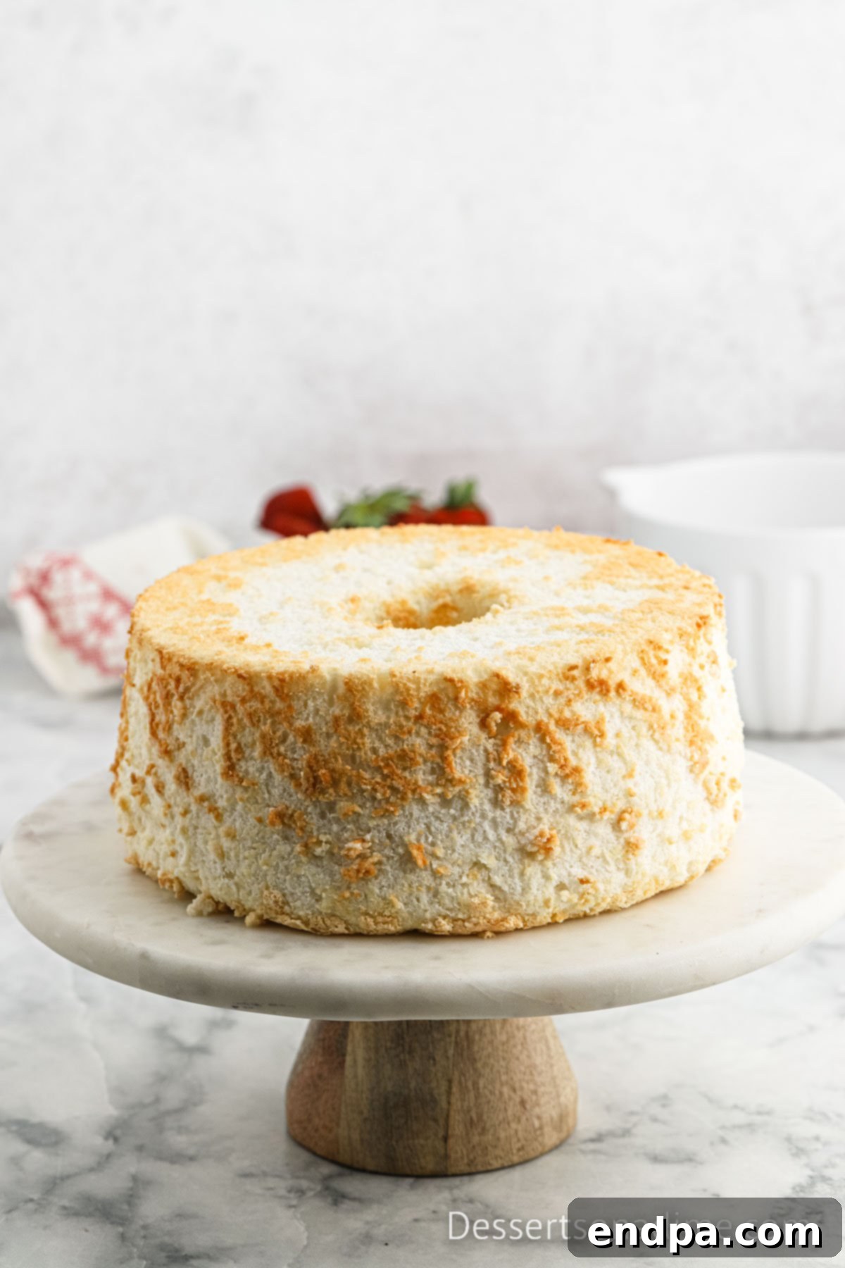 Baked Angel Food Cake on a cake stand, perfectly released from the pan.