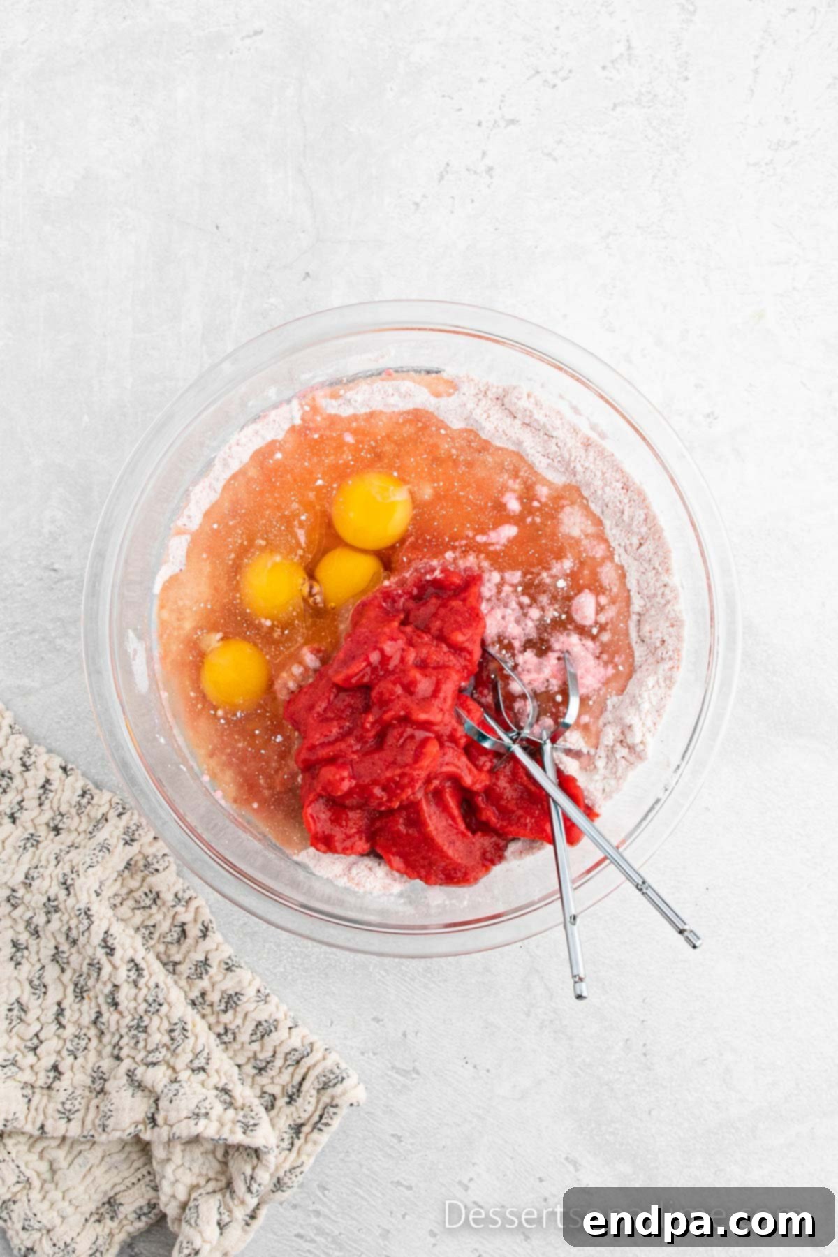 Paula Deen's Signature Strawberry Cake 6 Wet ingredients including strawberry puree, eggs, oil, and water being added to the dry cake mix and blended with an electric mixer until smooth.