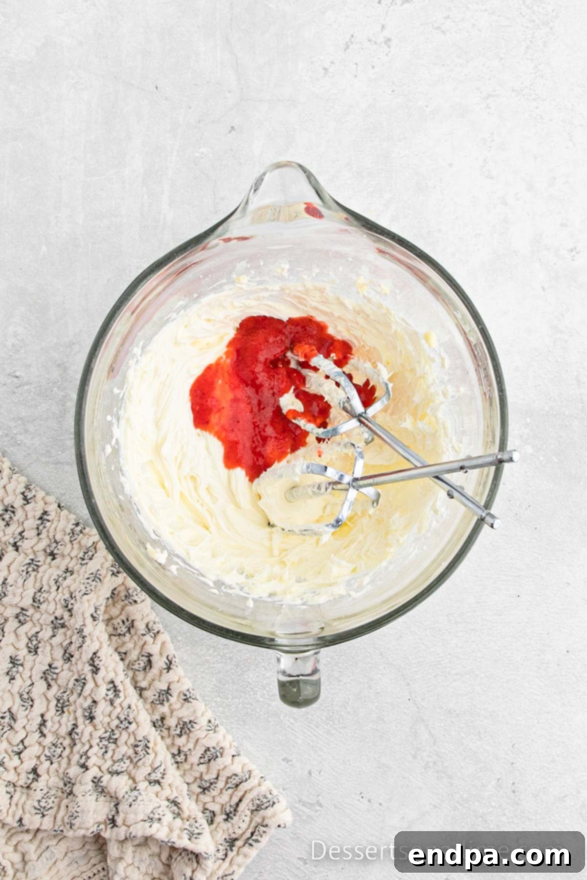 Paula Deen's Signature Strawberry Cake 9 Remaining strawberry puree being added to the butter and cream cheese mixture in a mixing bowl for the frosting.
