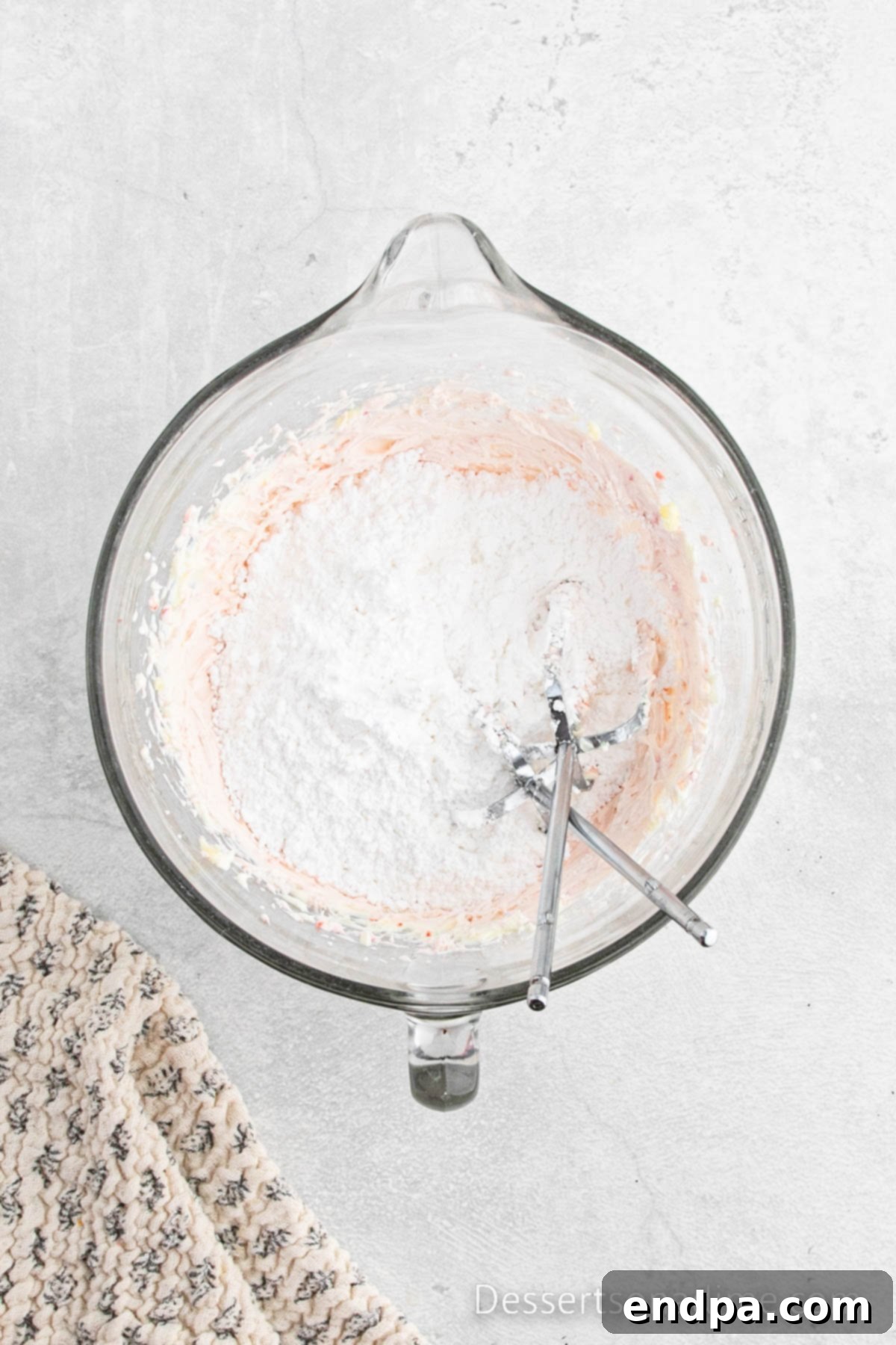 Paula Deen's Signature Strawberry Cake 10 Powdered sugar being gradually added to the strawberry cream cheese frosting mixture in a bowl and combined until smooth.