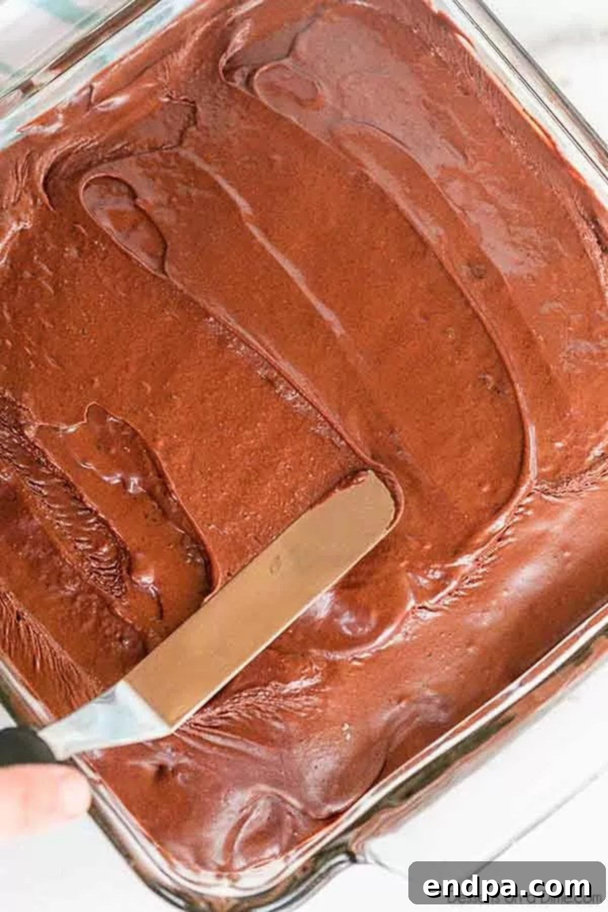 A whole pan of depression cake with a spatula frosting the cake. 