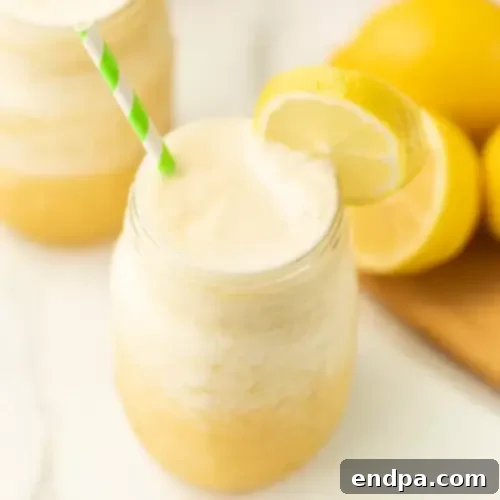 A vibrant Pineapple Lemonade Slushie in a tall glass, garnished with a lemon slice and a pineapple wedge.