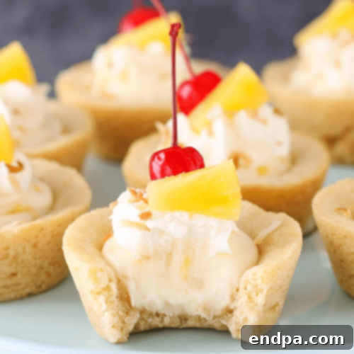 Mini Pina Colada Cookie Cups, with a coconut cookie crust and pineapple cheesecake filling, topped with whipped cream.