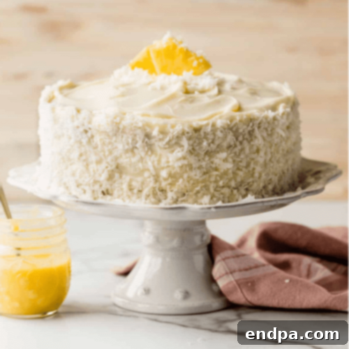 A moist Pineapple Coconut Cake with creamy frosting and toasted coconut flakes.
