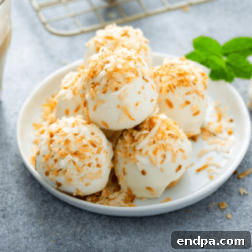 Decadent Pina Colada Truffles, garnished with coconut flakes and a maraschino cherry.