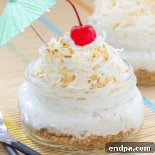 Individual Pina Colada Pie Jars, layered with creamy filling and topped with whipped cream and pineapple.