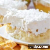 A slice of Pina Colada Poke Cake, showing the moist cake soaked with coconut cream and topped with whipped cream.