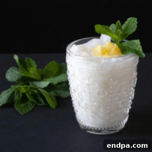 A creamy Pineapple Coconut RumChata Cocktail, garnished with a pineapple wedge and toasted coconut.