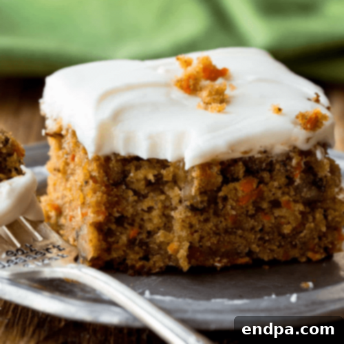A moist Pineapple Carrot Cake generously topped with creamy cream cheese frosting.