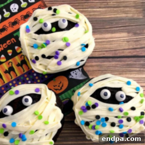 Delightful Mummy Cupcakes decorated with white frosting bands and candy eyes peeking out.