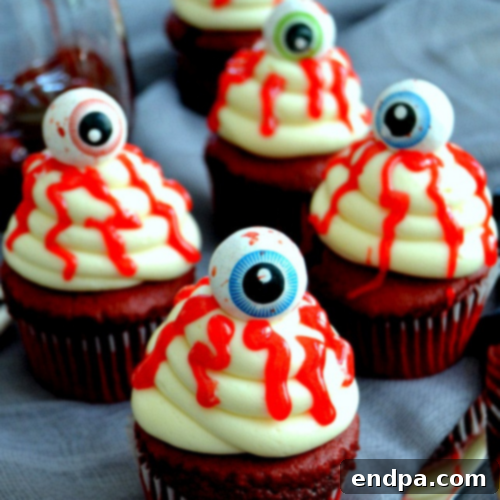 Gruesome Bloody Eyeball Cupcakes with white frosting, red gel veins, and edible gummy eyeballs.