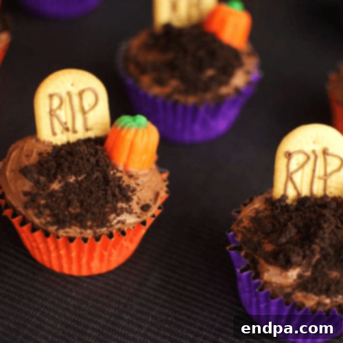 Spooky Graveyard Cupcakes adorned with crushed cookie 'dirt', candy tombstones, and gummy worms.