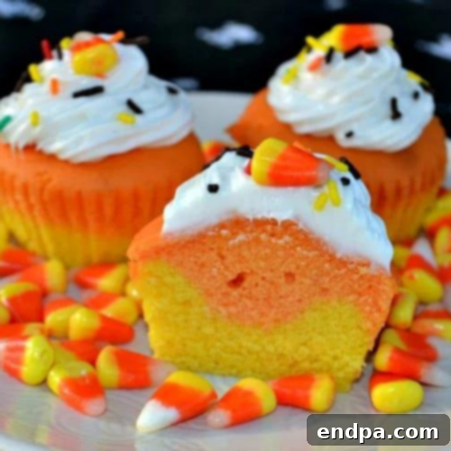 Festive Candy Corn Cupcakes displaying the iconic white, orange, and yellow layers of frosting.